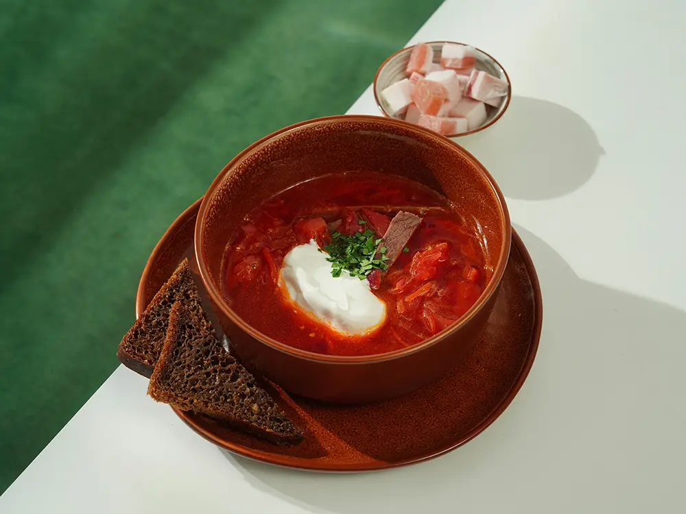 A bowl of Borscht garnished with sour cream and herbs